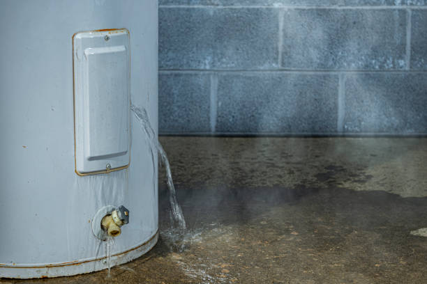 A close-up of a water heater leaking water on to the basement floor A close-up of water leaking out of an access panel of an electric water heater onto the concrete floor of a basement with a cinder block wall in the background. electric heater stock pictures, royalty-free photos & images