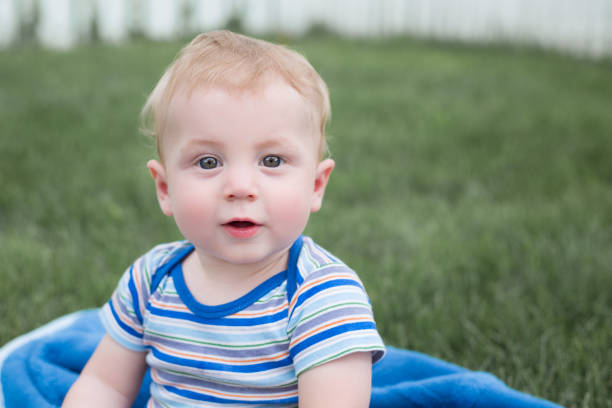 One year old baby outside in the grass. Baby playing outside in the backyard.