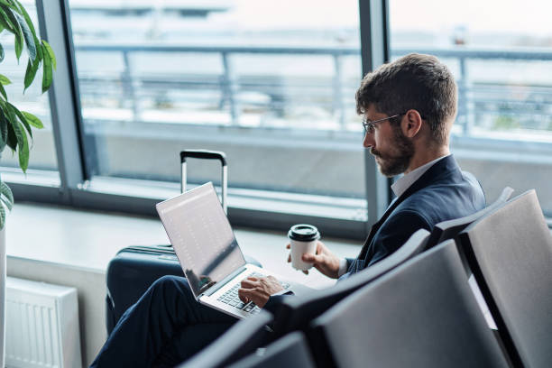 man with a takeaway coffee using a laptop in the airport departu stock photo