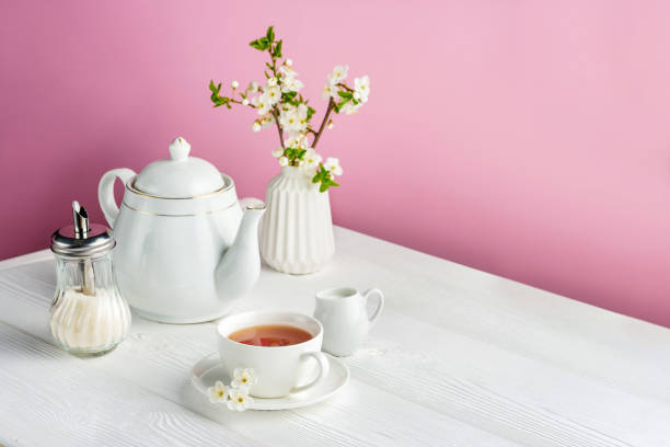 istock Tea set and cherry flowers on a pink background with copy space. 1372569709