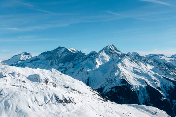 A wide shot of a snow capped mountain range in the French Alps on a sunny day.