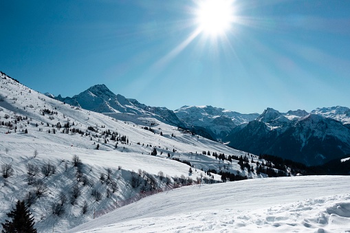 A wide shot of a snow capped mountain range in the French Alps on a sunny day.