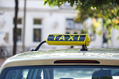 Close-up of a yellow taxi sign on the roof of a taxi or cap