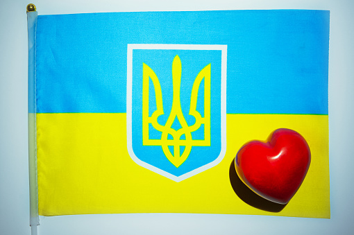 Flag and coat of arms of Ukraine and red heart close-up and place for text.