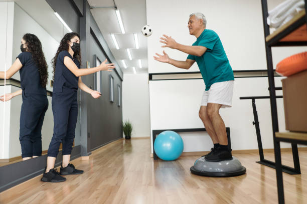 Senior patient catching ball on therapy ball stock photo
