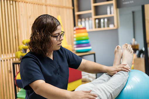 A latin female physical therapist working with a patient.