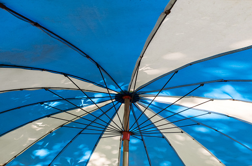 The metal frame inside the large two-tone umbrella near the beach, front view with the copy space.