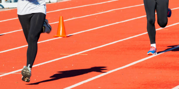 Two runners wearing black spandex running on a track