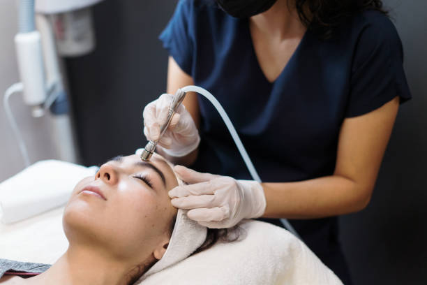 Young woman getting facial treatment with device A young latin woman getting a facial treatment with a device. microdermabrasion stock pictures, royalty-free photos & images