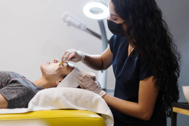 Esthetician applying skin product to woman with brush stock photo