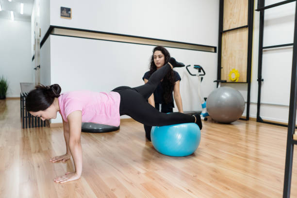 istock Young woman in physical therapy using exercise ball 1372583284