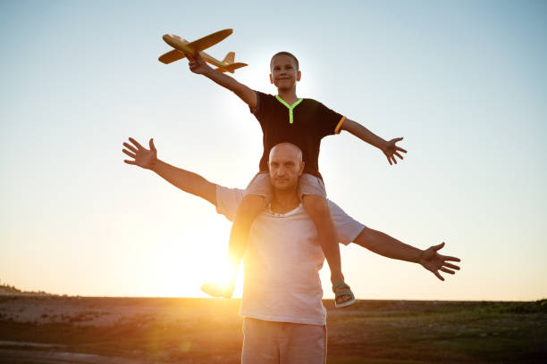 istock Dad and son launch a plane at sunset in summer 1372585447