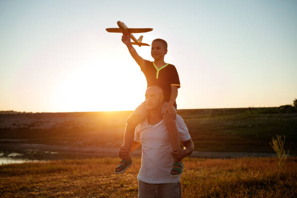 istock Dad and son launch a plane at sunset in summer 1372585774