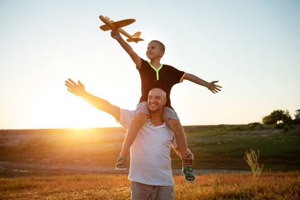 istock Dad and son launch a plane at sunset in summer 1372585941
