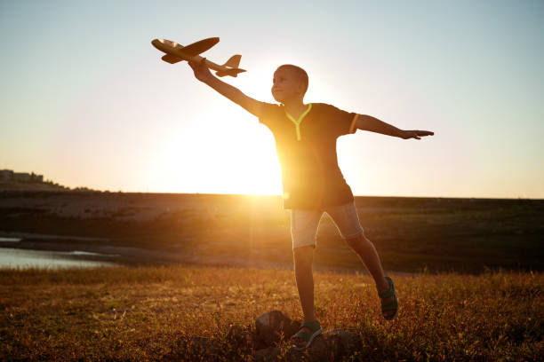 istock boy launches the plane on a background of sunset sky 1372586820