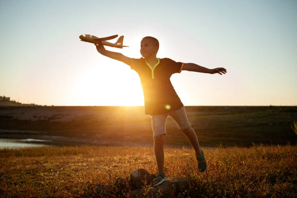 istock boy launches the plane on a background of sunset sky 1372587485