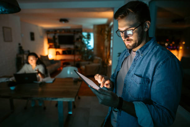 Portrait of mid adult white businessman holding digital tablet Portrait of mid adult white businessman holding digital tablet and standing next to the window in his office tired after work stock pictures, royalty-free photos & images
