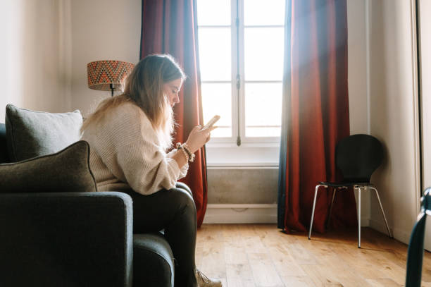 istock Young woman at home using a smart phone 1372592397