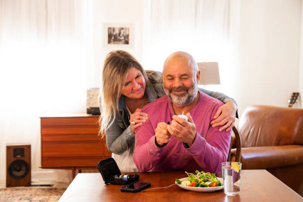 Managing diabetes with love and support A diabetic patient checking his blood sugar at home with the support of his wife. Consistent monitoring of blood sugar is an important part of managing diabetes. Photographed in North America diabetes stock pictures, royalty-free photos & images