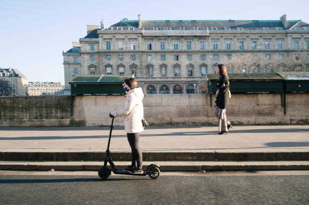 Paris, France - 15 February 2022: A woman riding an electric push scooter, while another one walks, in Paris, France