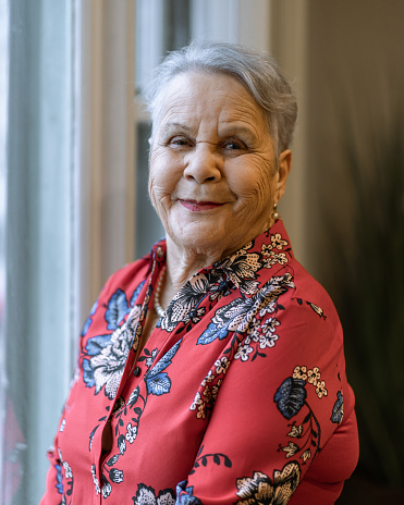Senior latin woman at home smiling and looking at camera