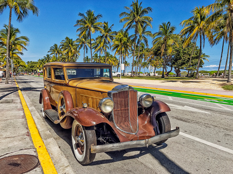 Havana, Cuba - December 9th 2022: Classic vintage cars driving along the Malecon at old Havana during dusk hour. Sunset lighting the face of a cuban girl in the car. Malecon is iconic spot for tourists, also the most popular place for cubans to hang out.