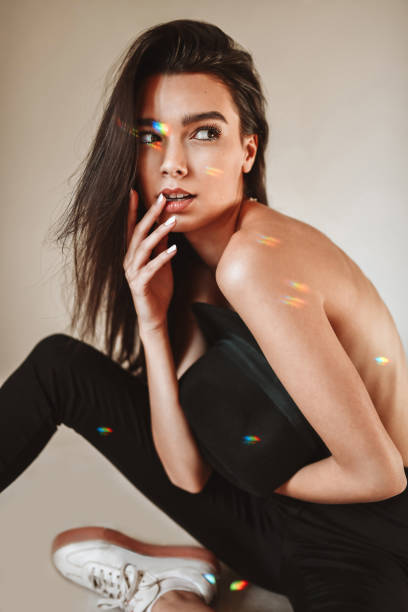 istock Beautiful Female Covering Herself With Hat While Getting Spotlight On Her And Sitting Down 1372599621