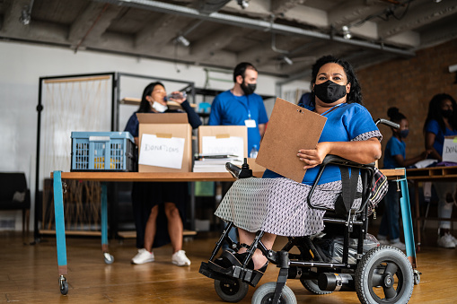 Portrait of a disabled mature woman working in a community charity donation centre - wearing protective face mask