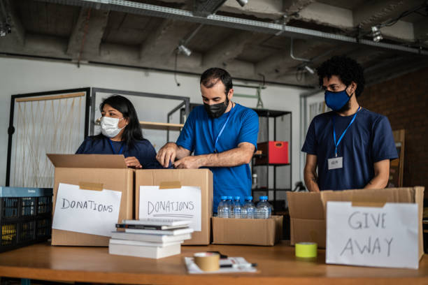 istock Group of volunteers working in community charity donation centre - using protective face mask 1372604852