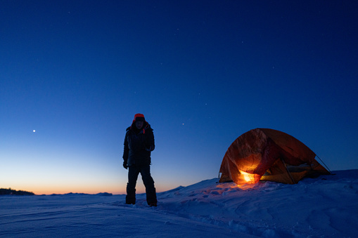man camping in ice lake in winter