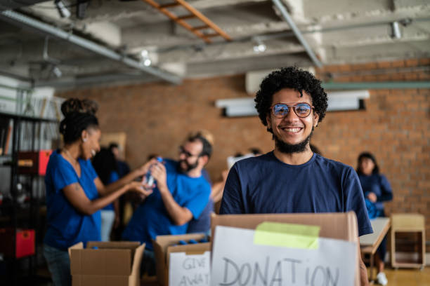 ritratto di un giovane che tiene in mano una scatola di beneficenza - volunteer organized group casual charity and relief work foto e immagini stock
