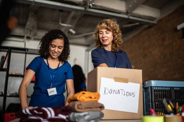 volunteers arranging clothes donations in a community charity donation center - schenking stockfoto's en -beelden