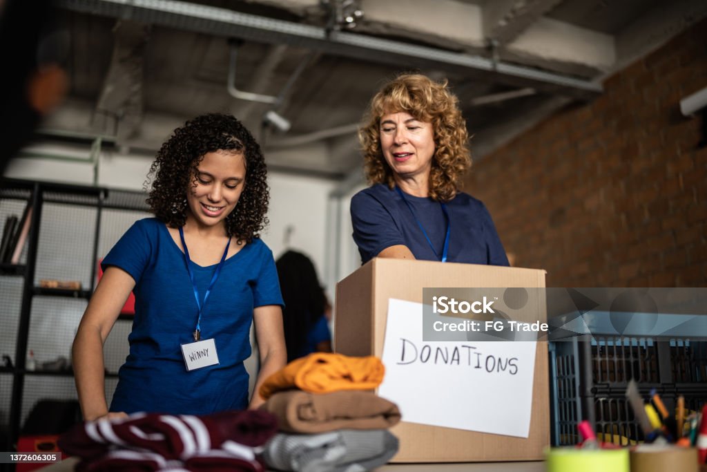 Volunteers arranging clothes donations in a community charity donation center Donation Box Stock Photo