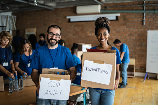 Portrait of volunteers holding charity boxes in a community center