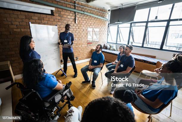 Mature Man Talking In A Meeting At A Community Center Including A Disabled Person Stock Photo - Download Image Now