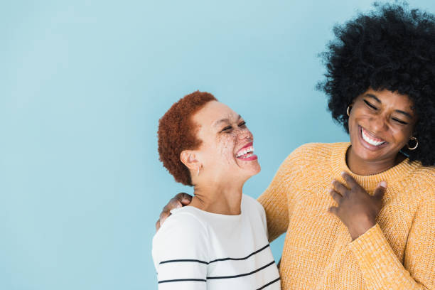 Female friends share a joke The female friends laugh at a joke together.  They both have the same sense of humor. short stature stock pictures, royalty-free photos & images