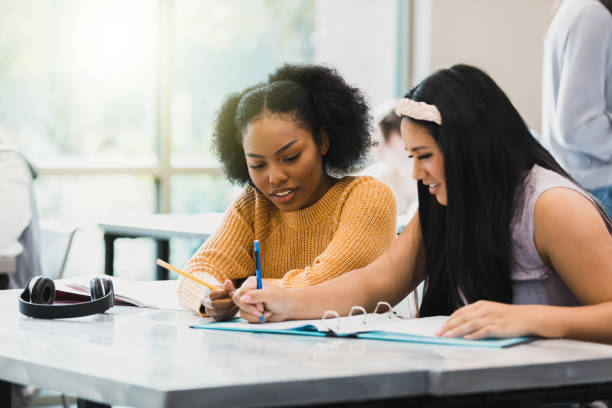 Two female students studying after school Two female high school friends work on a project or study together after class. high school high school student science multi ethnic group stock pictures, royalty-free photos & images