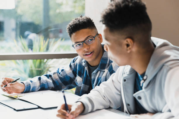 Male high school friends studying together A teenage boy talks to his friend as they study for a test together. high school student stock pictures, royalty-free photos & images