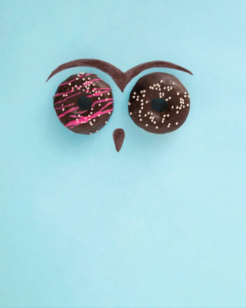 istock Doughnuts with pink and white decorations making owl face. Fun with sweets. Food love concept aesthetic abstract idea 1372616103