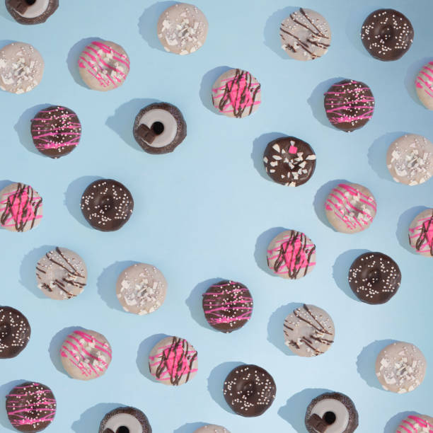 istock Doughnuts in row making pattern.Colorful food design. Flat lay aesthetic on a soft blue background copy space 1372616604