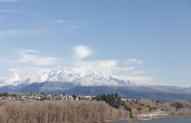 The snow-capped Coast Mountains stand in southwestern British Columbia. Foreground shows the cities of Coquitlam and Port Coquitlam by the Fraser River in Metro Vancouver. .