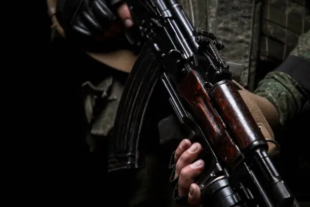 Closeup photo shoot of soldier's hand holding machine gun. Man is wearing military uniform and wach.