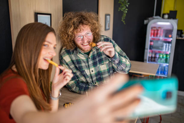 istock Two friends having fun and taking selfie in fast food restaurant 1372625421