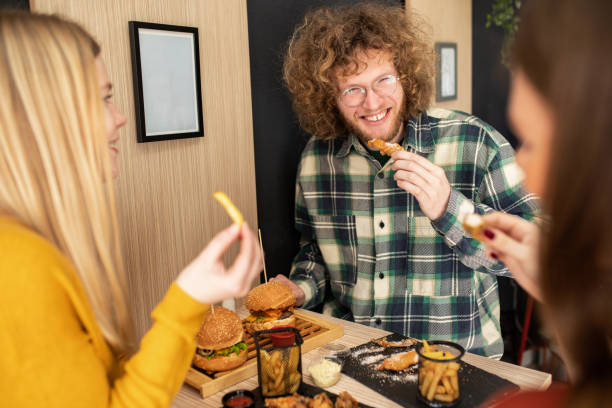 tre amici che si godono il loro tempo insieme in un fast food - deep fried people fried chicken foto e immagini stock