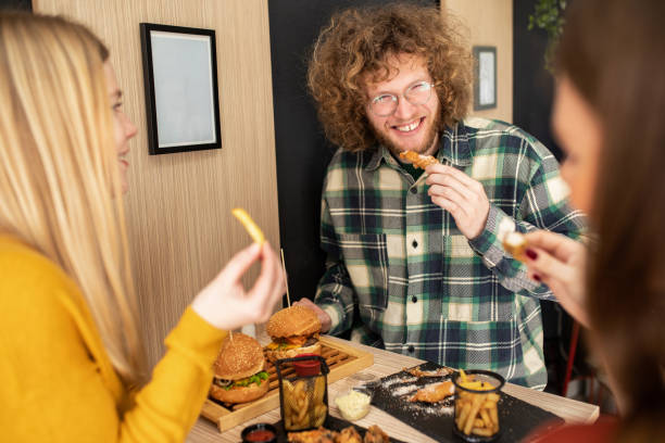 трое друзей наслаждаются временем, проведенным вместе в ресторане быстрого питания - deep fried people fried chicken стоковые фото и изображения