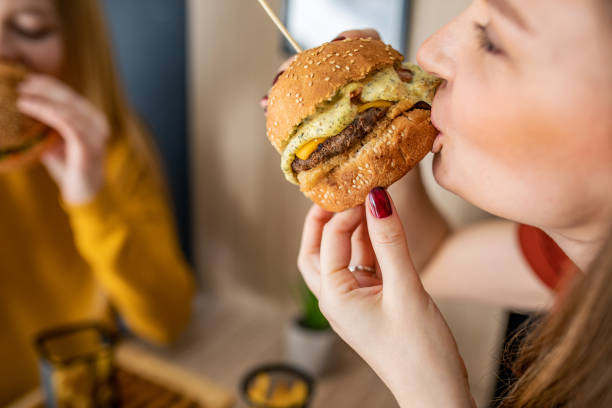 istock Young woman eats a burger with triple cheese 1372626698