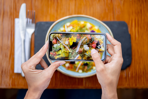 Close-up of a customer taking pictures of the food plate while eating at a restaurant - using phone concepts