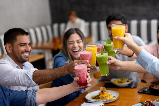 Happy group of people making a toast at a restaurant with non-alcoholic drinks and smiling