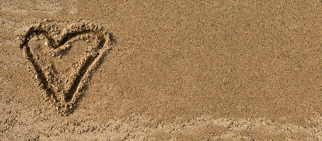 Top view of heart symbol written on wet sand, copy space, banner.