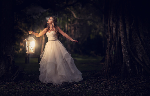 Young latin girl holding an old lamp in the dark